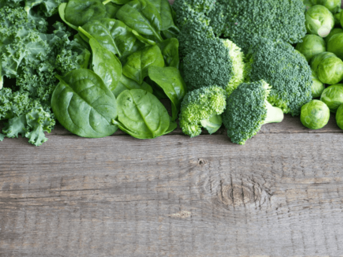 Kale, spinach, broccoli, Brussels sprouts arranged on wooden table